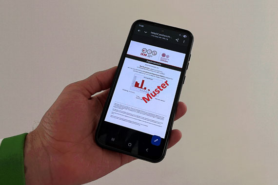 Eine Hand hält ein Handy, wo das IKM-Ergebnis angeziegt wird.